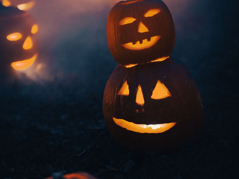 Carved jack-o'-lanterns glowing orange against a dark blue night.